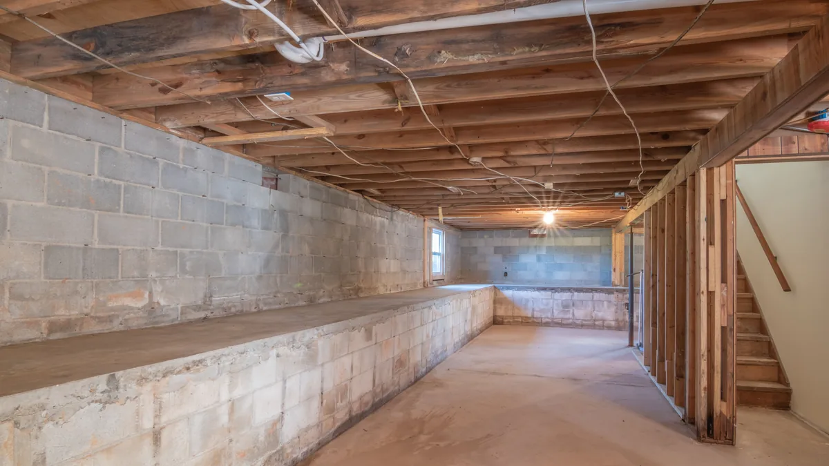 Unfinished basement with bare concrete floor and exposed structure, ready for a floor coating