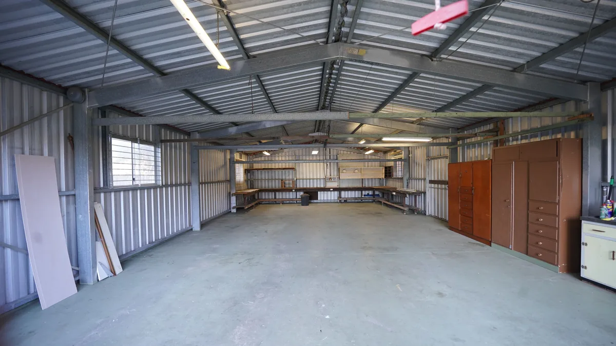 Empty industrial garage with bare concrete floor and metal walls