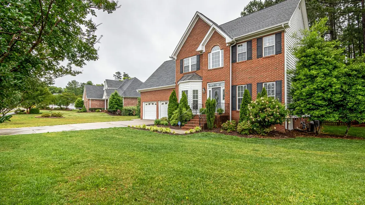Two-storey brick house with a manicured lawn and mature trees