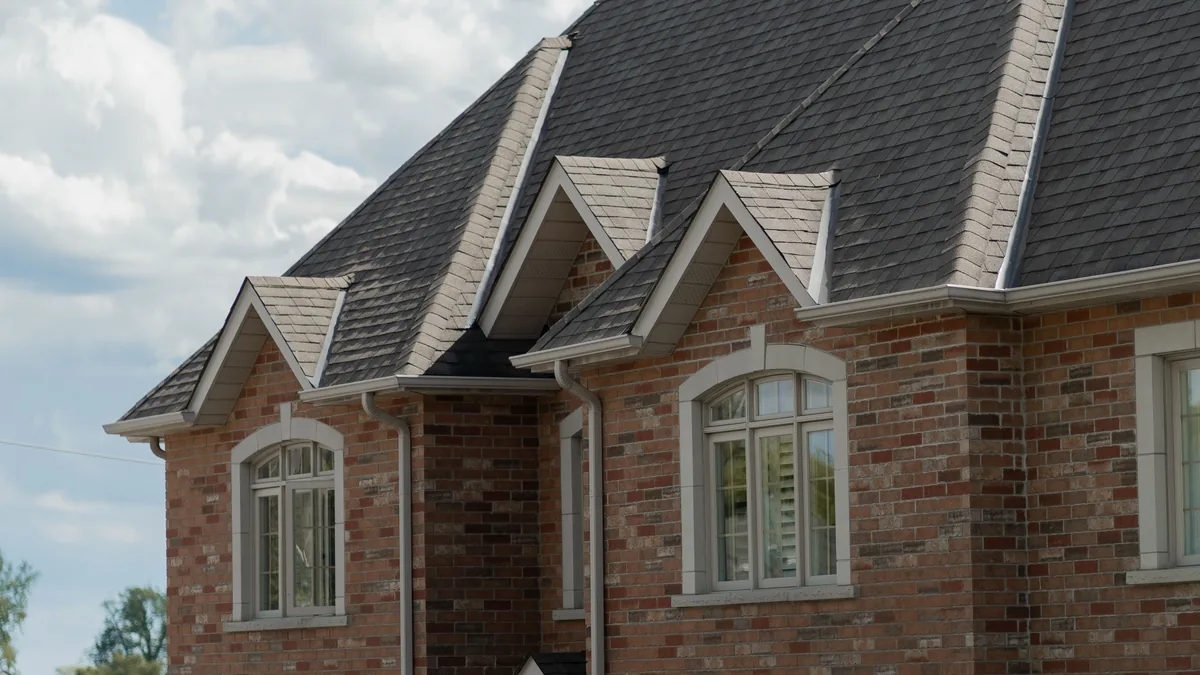 Brick house with a gable roof on a tree-lined street