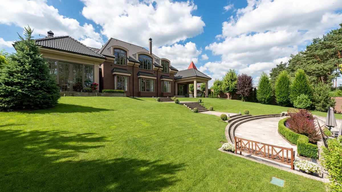 Established brick house with a manicured lawn and mature planting