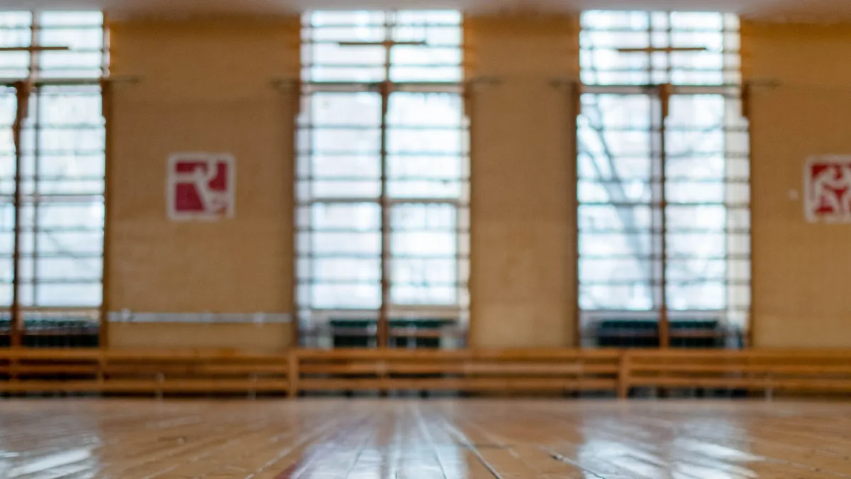 Empty gymnasium floor lit by tall windows