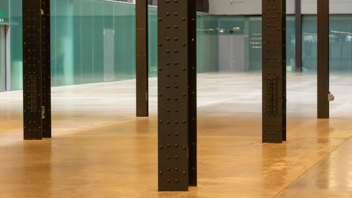 Industrial interior with a glossy poured floor reflecting steel columns