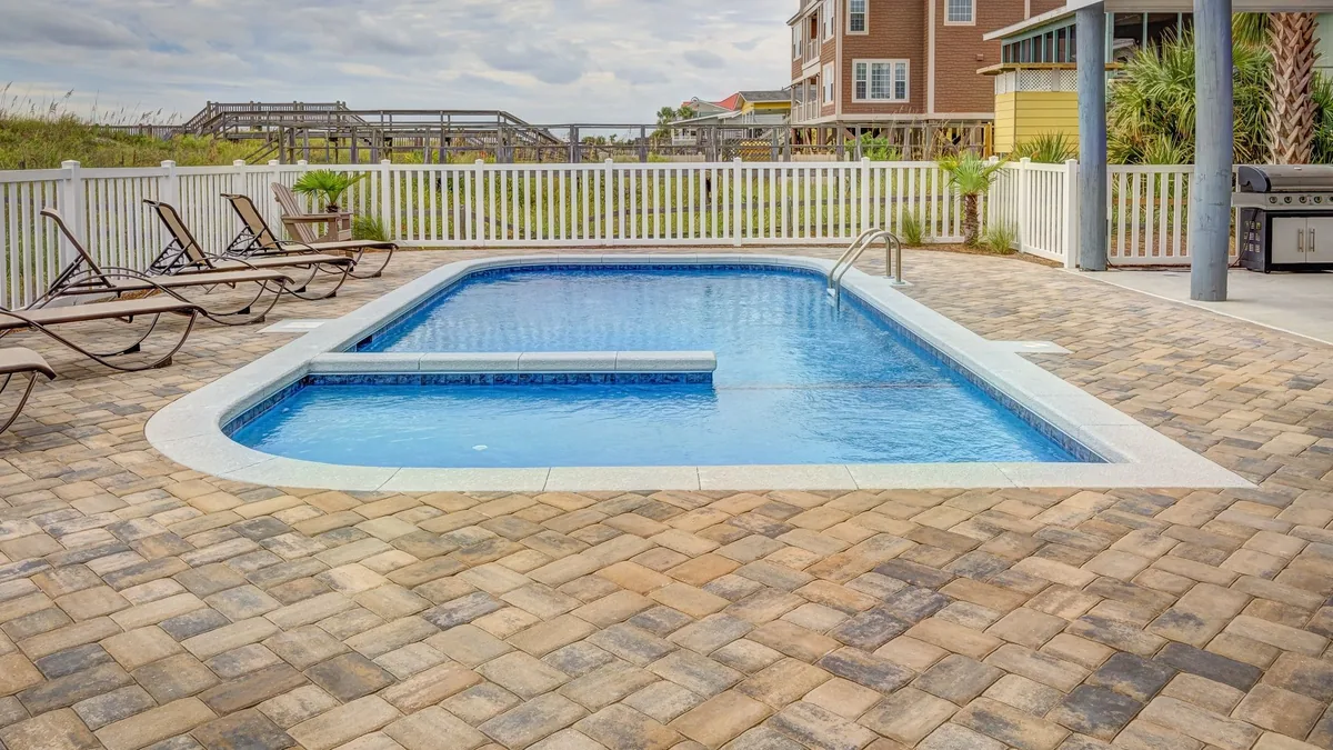 Pool deck surround with sun loungers beside a swimming pool