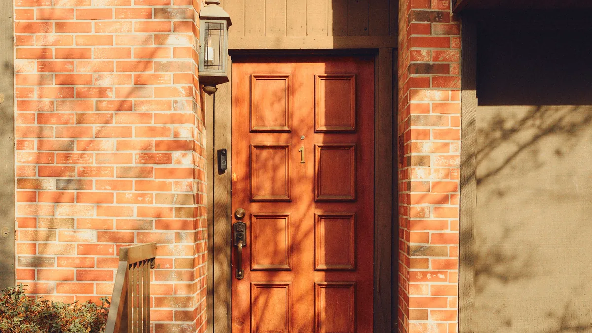 Covered brick porch entrance with a wooden front door